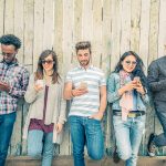 People leaning up against a fence looking at their smart phones. Here are some tips on how to seek and reward quality content. People have the right to encourage quality through conscious choice.